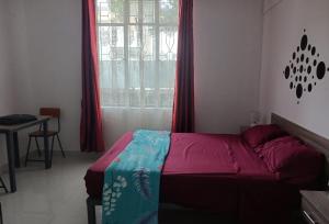 1 dormitorio con 1 cama y una ventana con cortinas rojas en An&Sy Family House, en Surinam