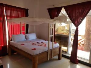 Cassandra Beach Resort في نونغوي: غرفة نوم بسرير مع مظلة ونافذة