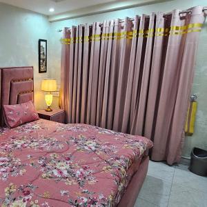 a bedroom with a bed with pink sheets and curtains at 1 Bed Luxury Apartment in Lahore