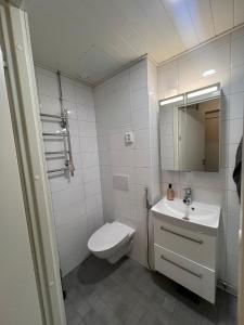 a white bathroom with a toilet and a sink at Roomvantaa in Vantaa