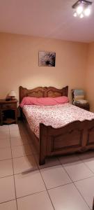 - une chambre avec un lit en bois et des draps roses dans l'établissement Omaha beach les braves, à Saint-Laurent-sur-Mer