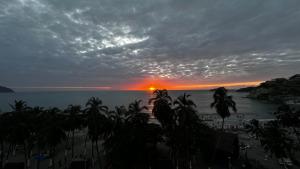 una puesta de sol sobre una playa con palmeras y el océano en Vista increíble Chirama Rodadero, en Santa Marta