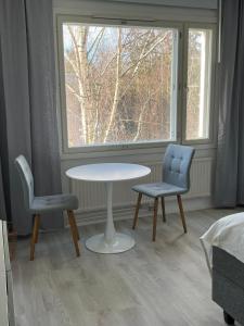 uma mesa e duas cadeiras num quarto com uma janela em Roomvantaa em Vantaa