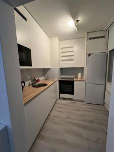 uma cozinha com armários brancos, um lavatório e um frigorífico em Roomvantaa em Vantaa