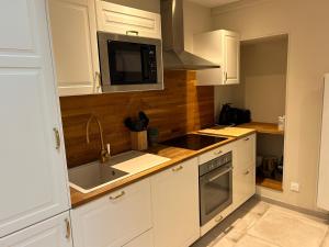 a kitchen with white cabinets and a sink and a microwave at Maison Grandjean in Bligny-lès-Beaune