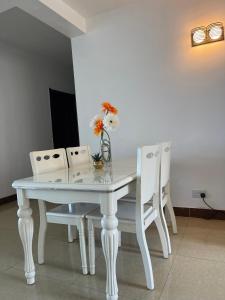 a white dining room table with two chairs and a vase with flowers at Arrabella Ocean View Home in Dar es Salaam