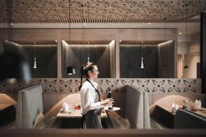 a woman standing in a restaurant with a plate at Sporthotel Bachmann in Gargellen