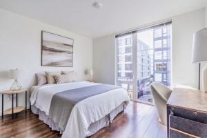 a white bedroom with a bed and a large window at Seattle Modern and Stylish Penthouse Apartment (Wifi, Pet Friendly, Rooftop) in Seattle