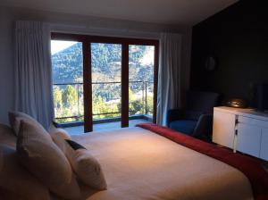 a bedroom with a large bed with a large window at The Alpine Retreat in Queenstown