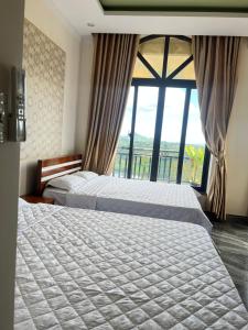 2 Betten in einem Hotelzimmer mit einem großen Fenster in der Unterkunft Hồng Ngọc 1 Hotel Tà Đùng in Biđong