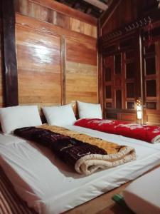 two beds in a room with wooden walls at Homestay Mạnh Châu in An Pon