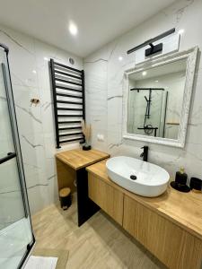 a bathroom with a white sink and a mirror at Apartamenty Kowalska III in Kościerzyna