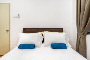 two blue pillows sitting on a white bed at Residensi Ostia by ZUJ in Bandar Baru Bangi