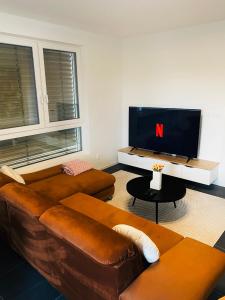 a living room with a brown couch and a tv at Luxusný apartmán v centre in Banská Bystrica