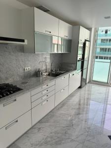 a kitchen with white cabinets and stainless steel appliances at Plaza Funchal - Coração da cidade in Funchal