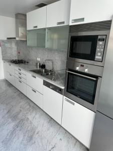 a kitchen with white cabinets and a microwave at Plaza Funchal - Coração da cidade in Funchal +3 photos
