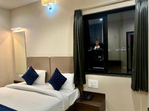a bedroom with a bed with blue and white pillows at Maruti Group of Hotels - The Shivam in Nāthdwāra