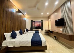 a bedroom with two beds and a flat screen tv at Maruti Group of Hotels - The Shivam in Nāthdwāra