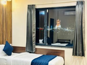 a bedroom with a window with a view of the city at Maruti Group of Hotels - The Shivam in Nāthdwāra