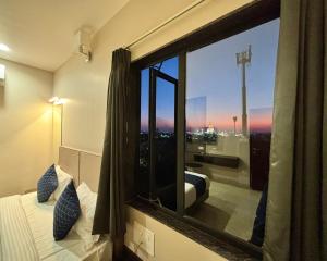 a bedroom with a window with a view of a city at Maruti Group of Hotels - The Shivam in Nāthdwāra