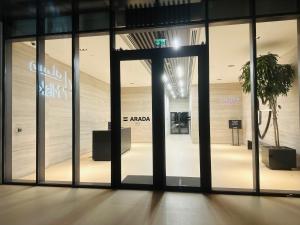 an open glass door of a store with a tree inside at Modern Sanctuary W/ Pool & Gym access in Sharjah