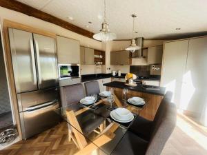 a kitchen with a glass table and stainless steel refrigerator at Rosie's Rest With Hot Tub in Barmby on the Moor