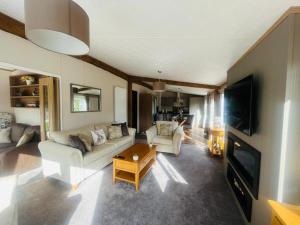 a living room with a couch and a tv at Rosie's Rest With Hot Tub in Barmby on the Moor +4 photos