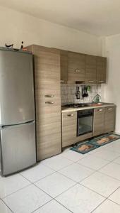 a kitchen with a stainless steel refrigerator and wooden cabinets at Casa París “Tropical” in Montañita