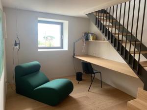 ein Wohnzimmer mit einem grünen Stuhl und einer Treppe in der Unterkunft Villa Tschaupp in Dorf Tirol