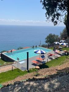 una piscina con sedie, ombrelloni e oceano di Villa Bice a Bergeggi