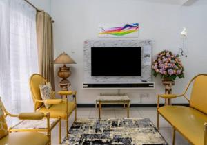 a living room with a flat screen tv and yellow chairs at Shah Alam Golden Homestay 4 Rooms, 3 Bathrooms Seksyen 7 near uitm icity in Shah Alam