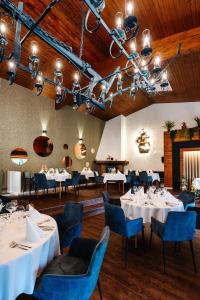 a dining room with white tables and blue chairs at Hotel Steineweiher in Saint-Vith