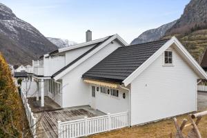a white house with a porch and mountains in the background at Bjørn og Jasmins plass in Lærdalsøyri