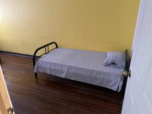 ein kleines Bett in einem Zimmer mit Holzboden in der Unterkunft El Parque Bed and Breakfast in Alajuela