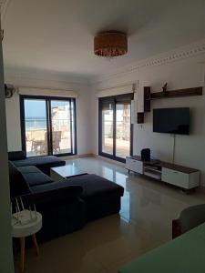 Appartement Yoff Virage vue panoramique sur mer في داكار: غرفة معيشة مع أريكة وتلفزيون بشاشة مسطحة