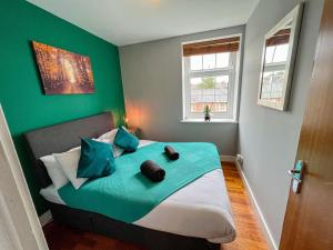1 Schlafzimmer mit einem Bett mit grünen Wänden und 2 Fenstern in der Unterkunft Modern Free Private Parking Central Reading 2 bedroom in Reading