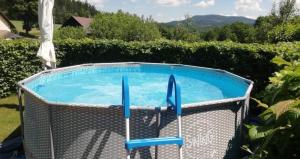 a swimming pool with two blue chairs around it at Chalupa Zlíčko in Vysoká Srbská