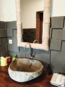 a bathroom with a stone sink and a mirror at Wooden House Pool View by Malathi Villas in Ubud