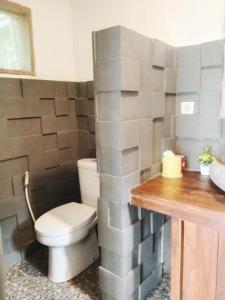a bathroom with a toilet and a wall made of blocks at Wooden House Pool View by Malathi Villas in Ubud