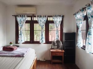 a bedroom with a bed and a window with a fan at Wooden House Pool View by Malathi Villas in Ubud