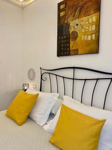 Un dormitorio con una cama con almohadas amarillas y una pintura en Bien-être Exclusive Apartment, en Taranto