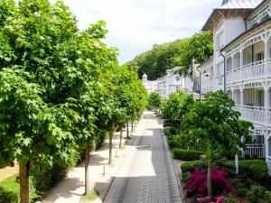 eine Straße mit weißen Gebäuden mit Bäumen und Sträuchern in der Unterkunft Ferienwohnung 16 im Seeschloss Binz - mit Meerblick in Binz