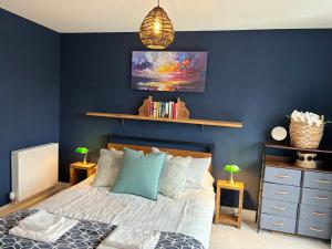 um quarto com uma parede azul com uma cama e uma prateleira em Modern Home Near Edinburgh City em Bonnyrigg