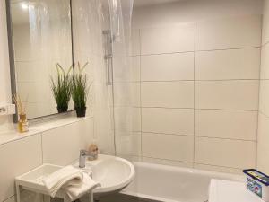 La salle de bains blanche est pourvue d'un lavabo et d'une baignoire. dans l'établissement Apartkeep Magdeburg 36, à Magdebourg