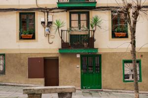 a building with green doors and windows and a bench at Acogedor apartamento en Bilbao in Bilbao