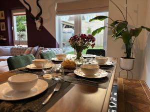 a dining room table with dishes and flowers on it at Modern Home Near Edinburgh City in Bonnyrigg