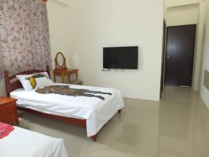 una camera da letto con due letti e una TV a schermo piatto di Village Tree B&B a Ji'an