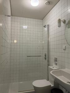 a bathroom with a shower and a toilet and a sink at Surf & Sea Suites in Parede