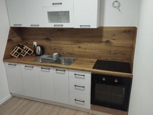 a kitchen with white cabinets and a wooden counter top at Apartman Nona in Kupres