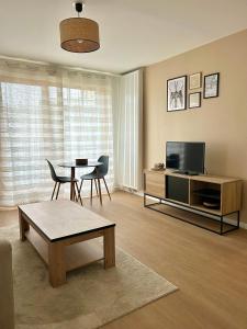 ein Wohnzimmer mit einem Tisch und einem TV in der Unterkunft Bel appartement lumineux résidentiel proche de Paris in Ivry-sur-Seine